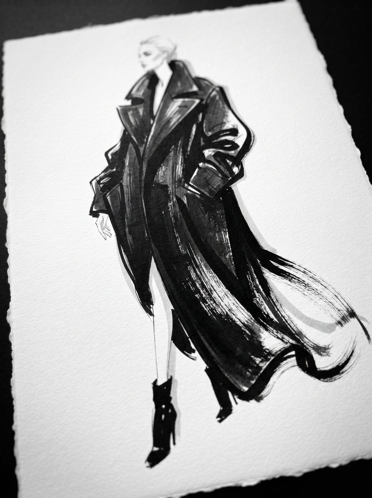 Tall fashion illustration of a sculptural coat in black sumi ink and warm brown wash on cotton paper